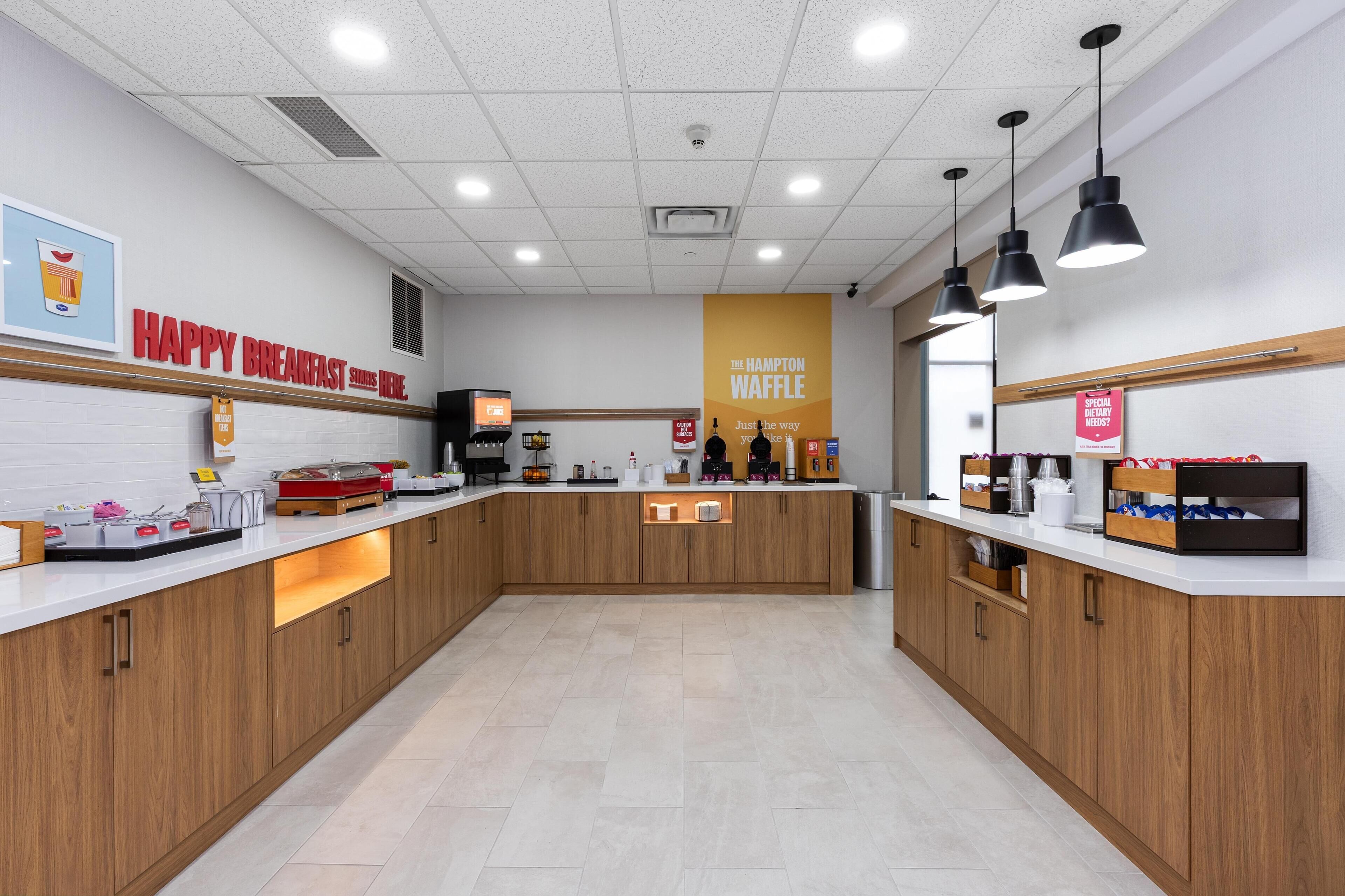 A modern kitchen with wooden cabinets, a white countertop, and overhead lighting.