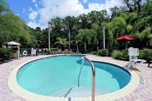 A circular pool with a metal ladder, surrounded by a brick walkway and lush greenery. - Hampton Inn & Suites Tampa-Wesley Chapel (Wesley Chapel)