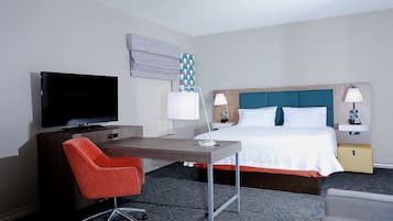 A hotel room with a bed, a desk with a chair, a television, and two bedside lamps.