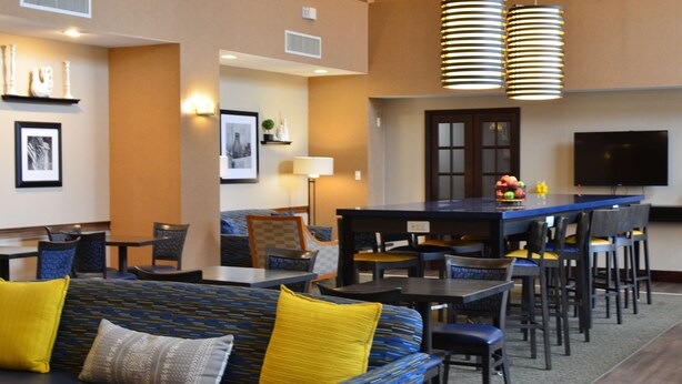 A hotel lobby with a seating area, a bar, and a television. - Hampton Inn & Suites Madisonville (Madisonville)