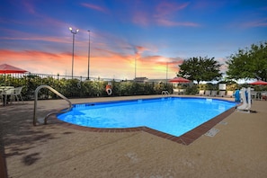 A swimming pool with a metal ladder, surrounded by a fence, and a sunset in the background. - Hampton Inn & Suites Houston - Rosenberg (Rosenberg)