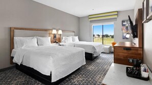 A hotel room with two beds, a desk with a coffee maker, a TV, and a large window with a view of the outdoors. - Hampton Inn & Suites Houston - Rosenberg (Rosenberg)
