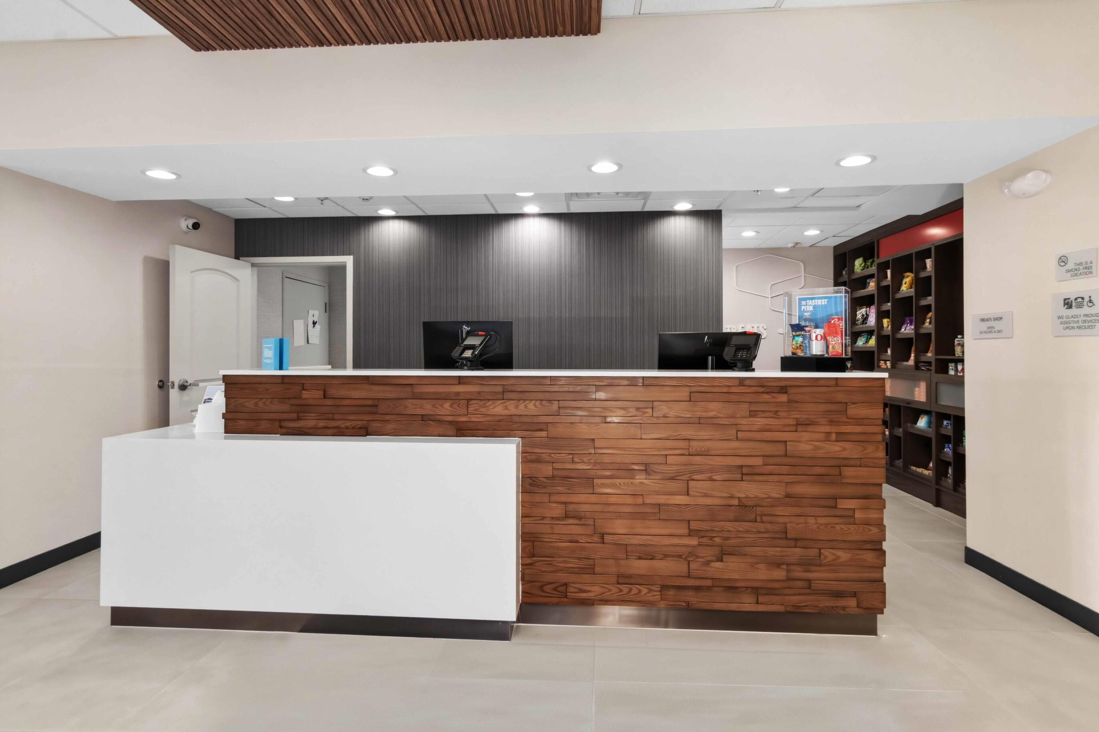 A reception desk with a wooden panel design, a digital screen, and a sign indicating a smoke-free area.