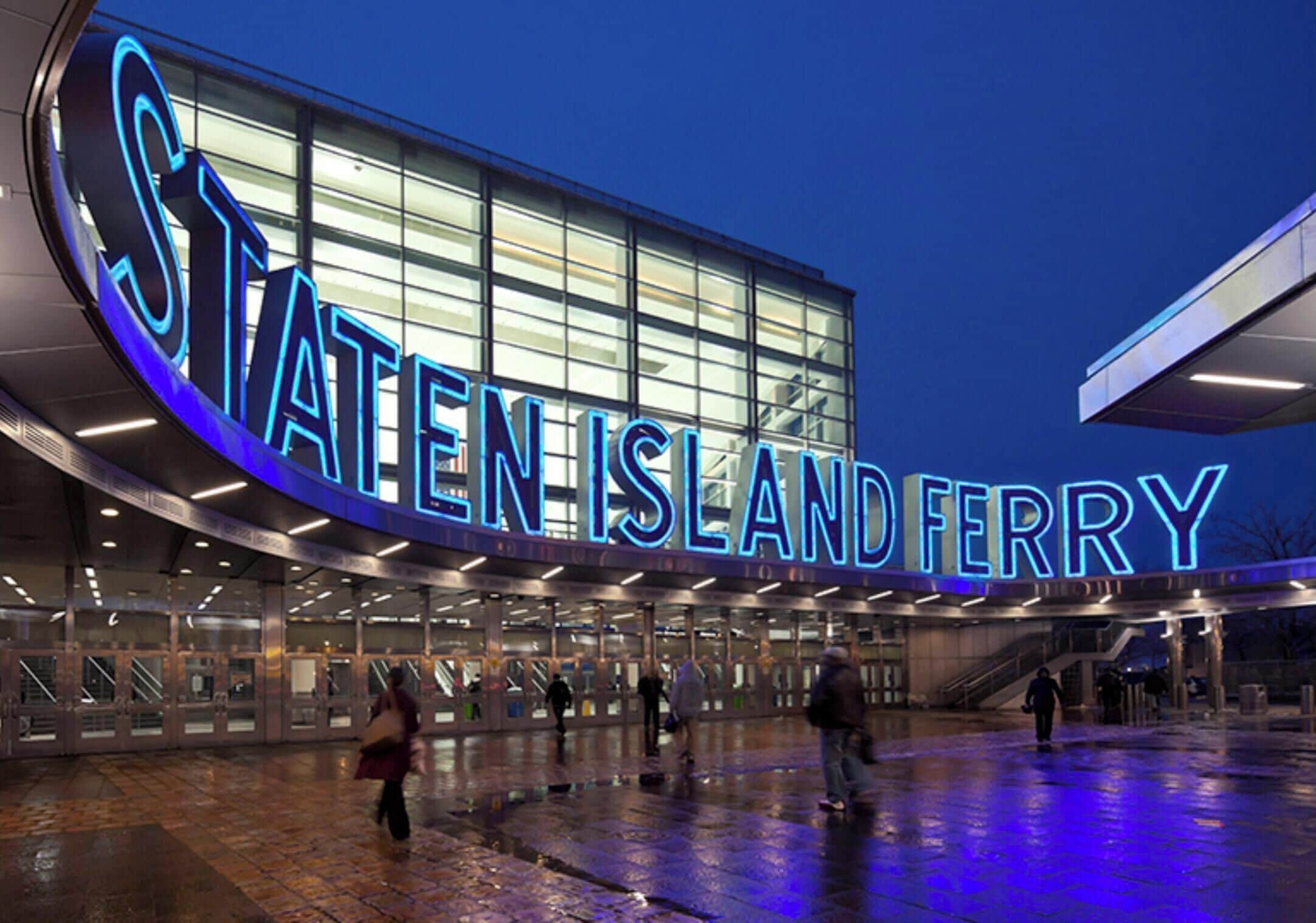 A modern building with a large illuminated sign reading 'STATEN ISLAND FERRY.'