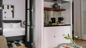 A modern room with a bed, a kitchenette, and a small round table with a vase.