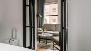 A modern hotel room with a sofa, a small round table with a vase, and a suitcase. - Duane Street Hotel Tribeca, Belvilla District 6 Formerly Sonder (New York)