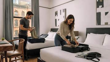 Een hotelkamer met twee bedden, een houten stoel, een tafel en een raam met gordijnen.