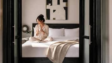 A bed with white bedding, a bedside table with a lamp, and a wall art piece.