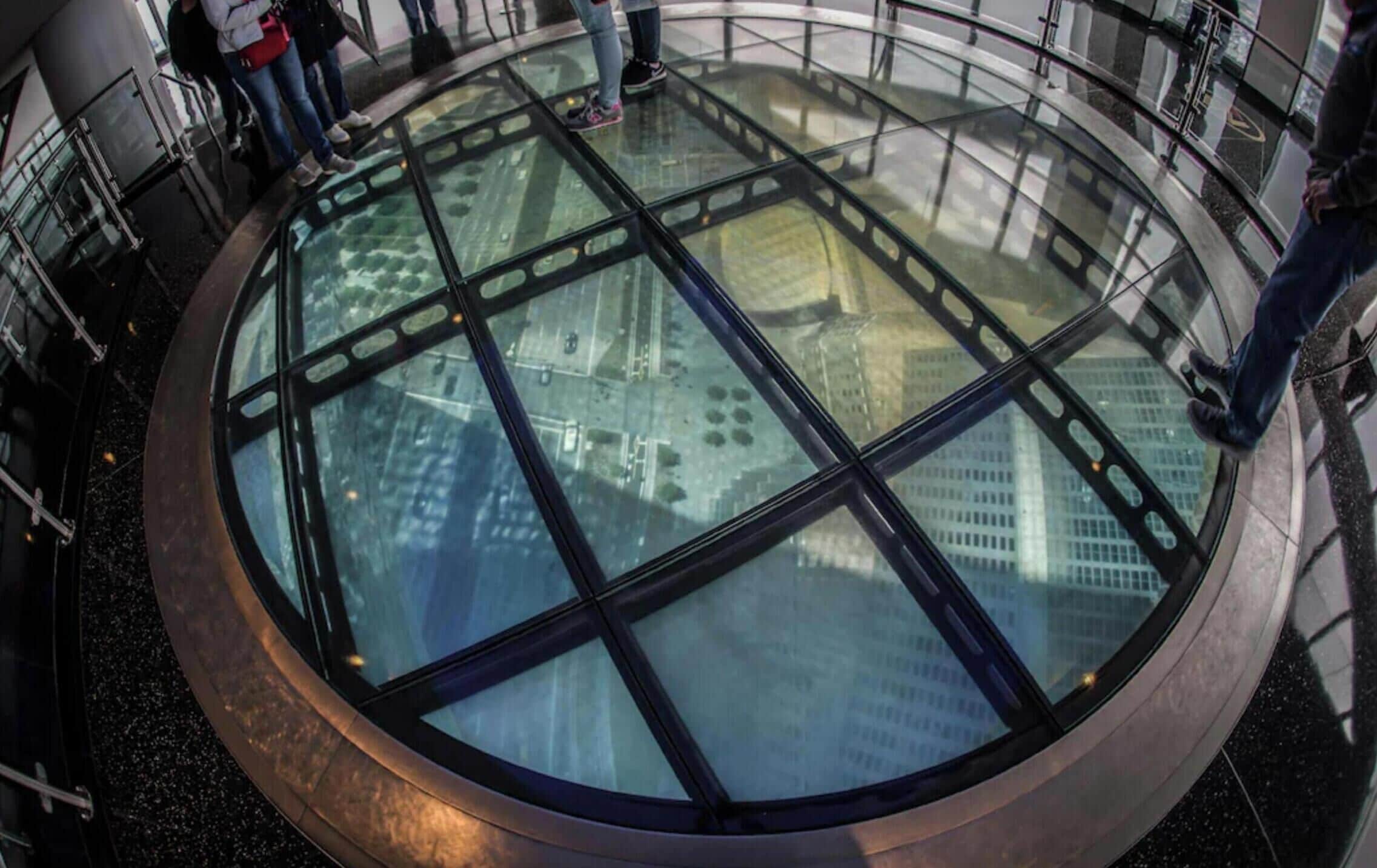 A circular glass floor with a view of buildings below.