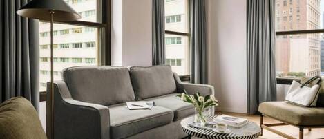 Un salon moderne avec un canapé gris, une table basse ronde et un lampadaire.