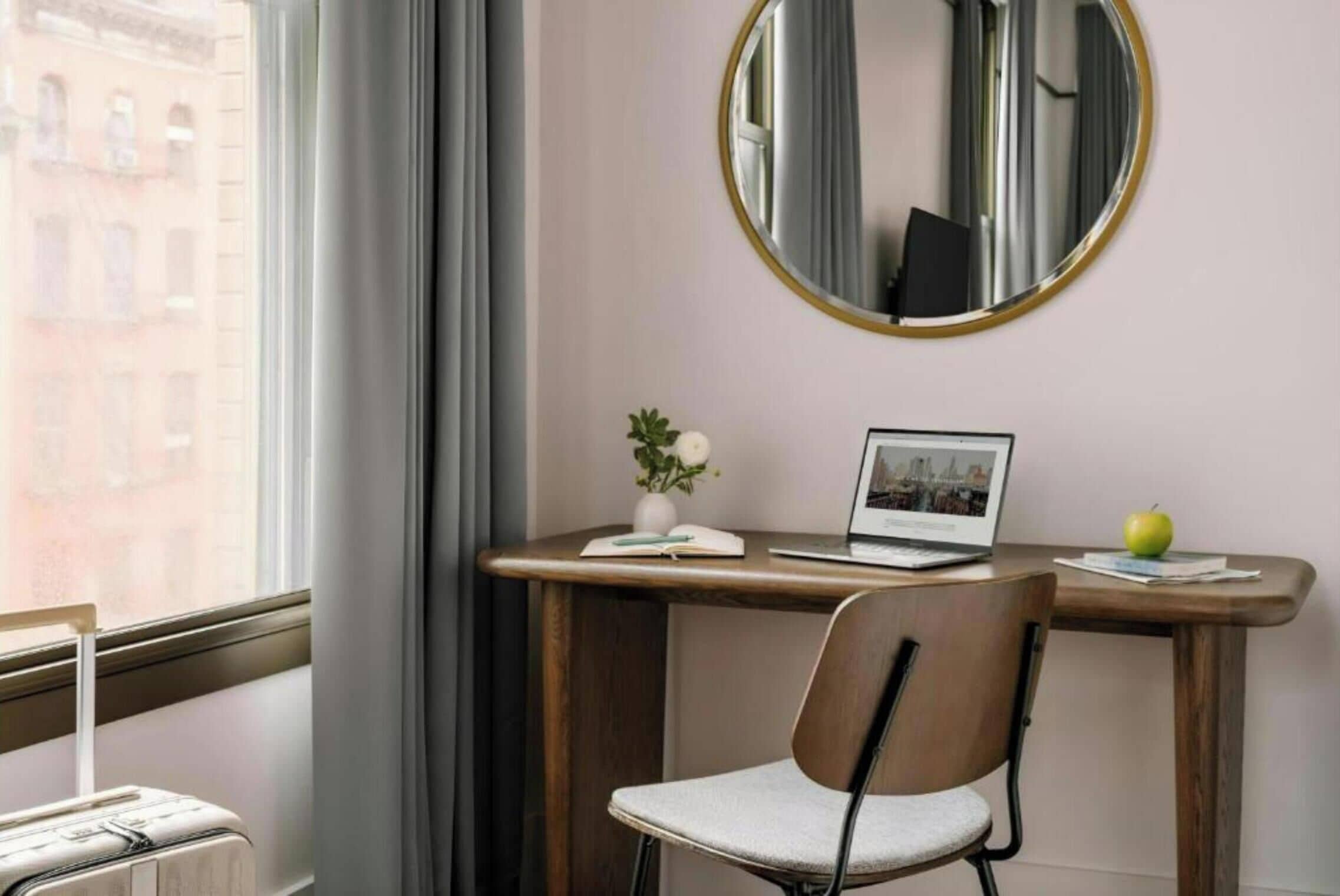 Une pièce comprenant un bureau, une chaise, un ordinateur portable et une valise.