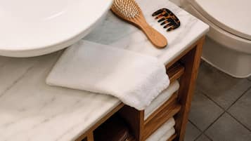 Une salle de bain avec un lavabo en marbre, des étagères en bois, une serviette, une brosse en bois et un peigne.