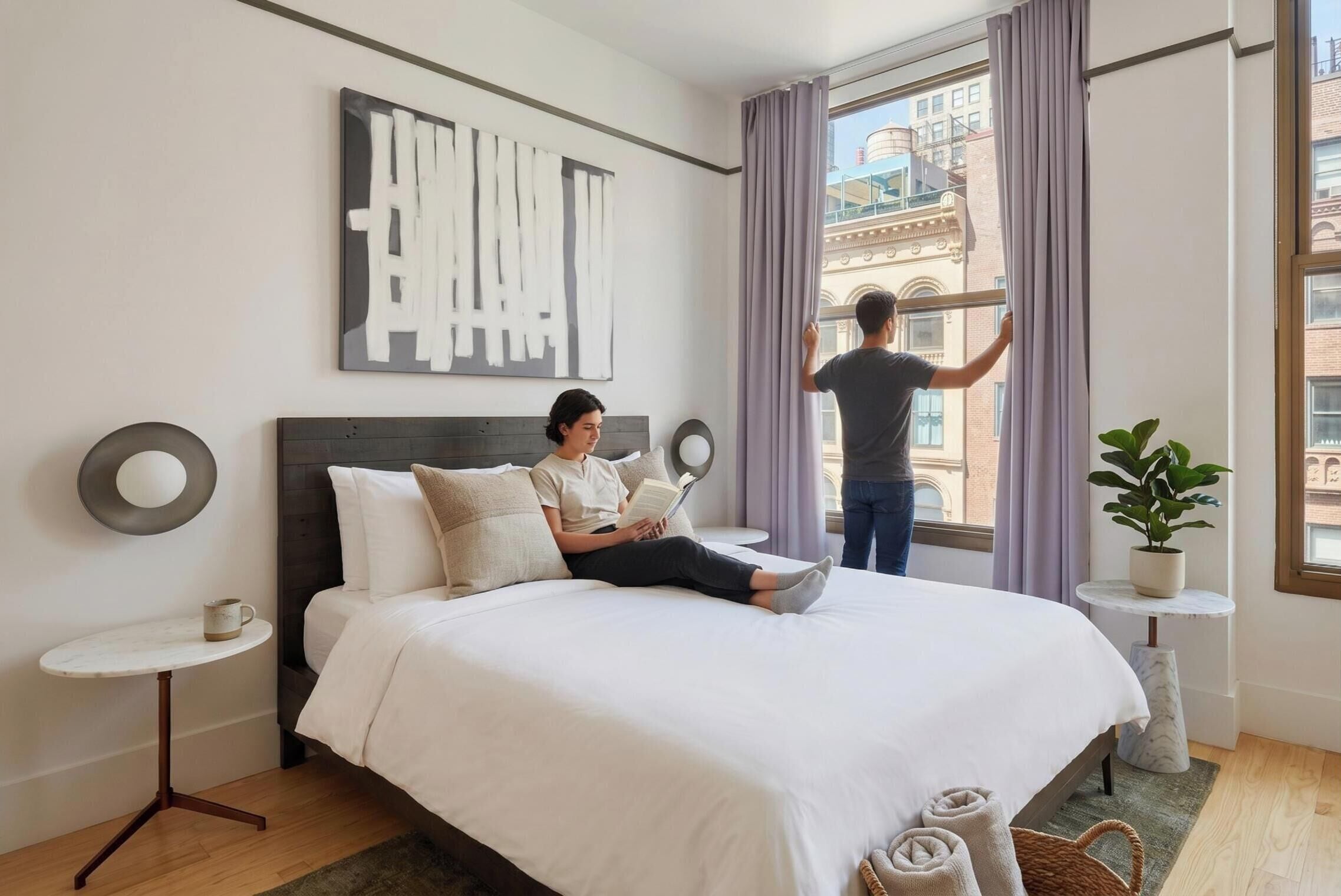 A hotel room with a bed, a bedside table, a potted plant, and a window with curtains.