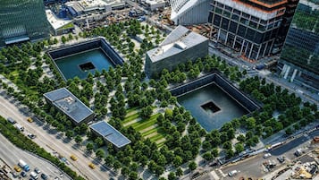 Vista aèria d'un paisatge urbà amb edificis moderns, una plaça central amb arbres i una font.