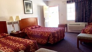 A hotel room with two beds, a desk, a chair, and a window with curtains.