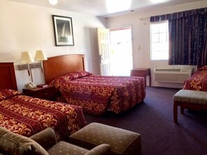 A hotel room with two beds, a desk, a chair, and a window with curtains.