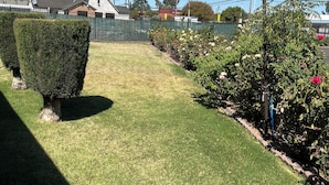 Une pelouse bien entretenue, agrémentée de haies taillées avec soin et d’une variété de plantes à fleurs.