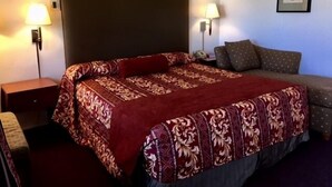 A hotel room with a large bed, two bedside lamps, a nightstand, and a framed picture on the wall.