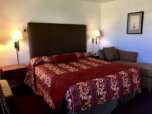 A hotel room with a large bed, two bedside lamps, a nightstand, and a framed picture on the wall.