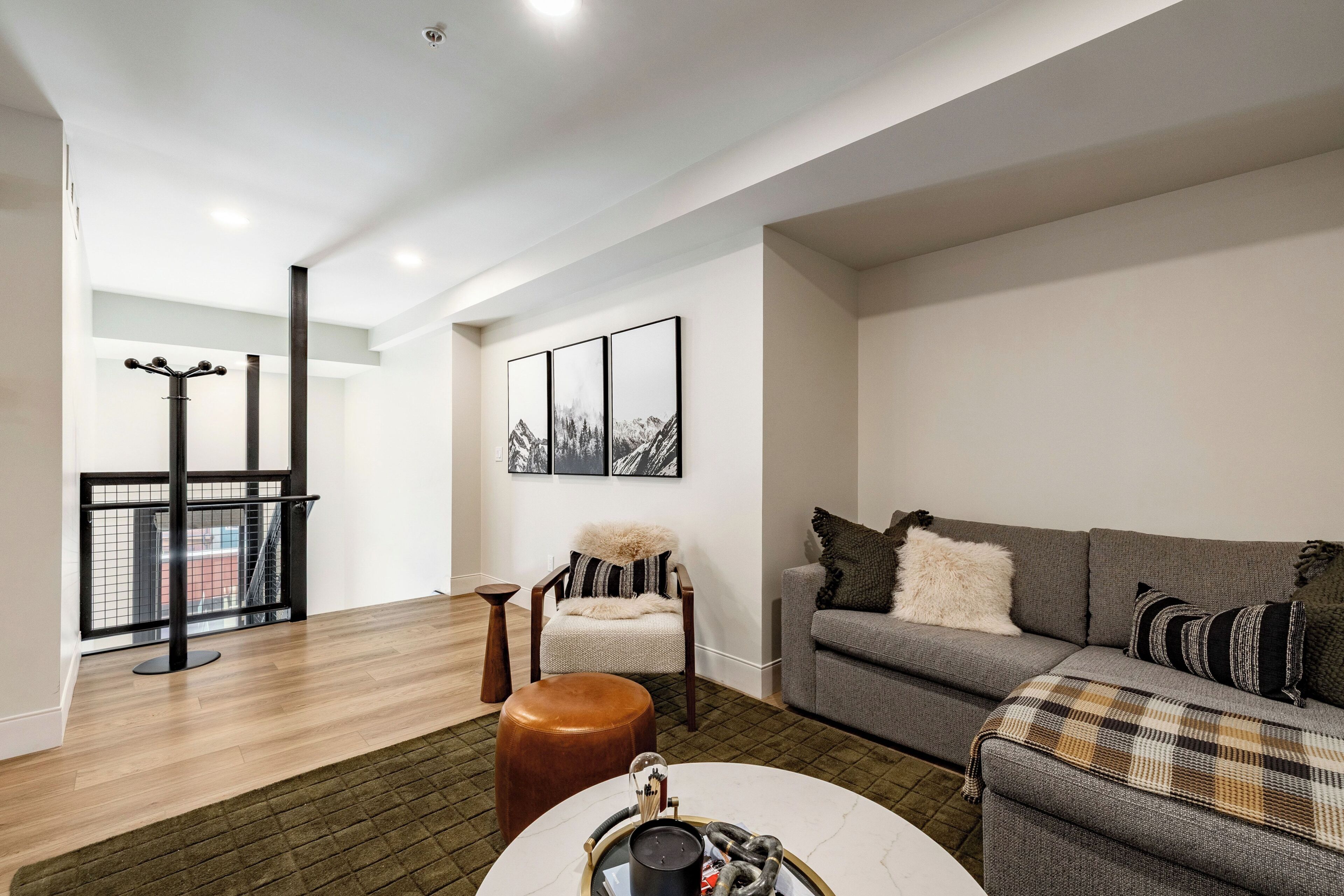 A modern living room with a grey sofa, a round coffee table, and a chair with a fur throw.