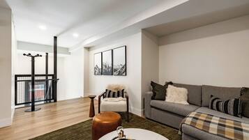 A modern living room with a grey sofa, a round coffee table, and a chair with a fur throw.