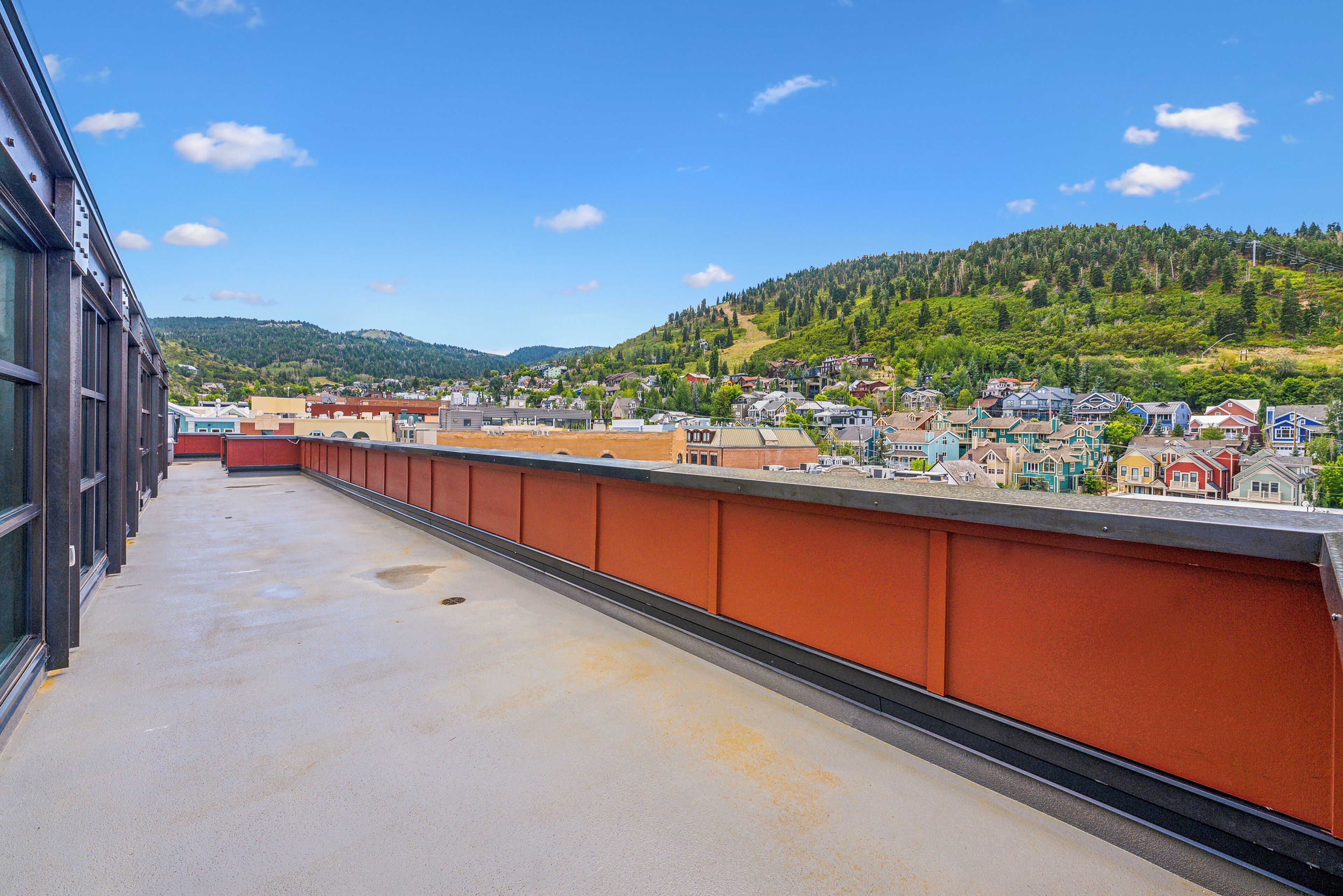 A balcony with a view of a town and hills.