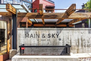 A building with the sign "MAIN & SKY" at 2011 HEBER AVE, featuring a concrete facade and wooden beams.