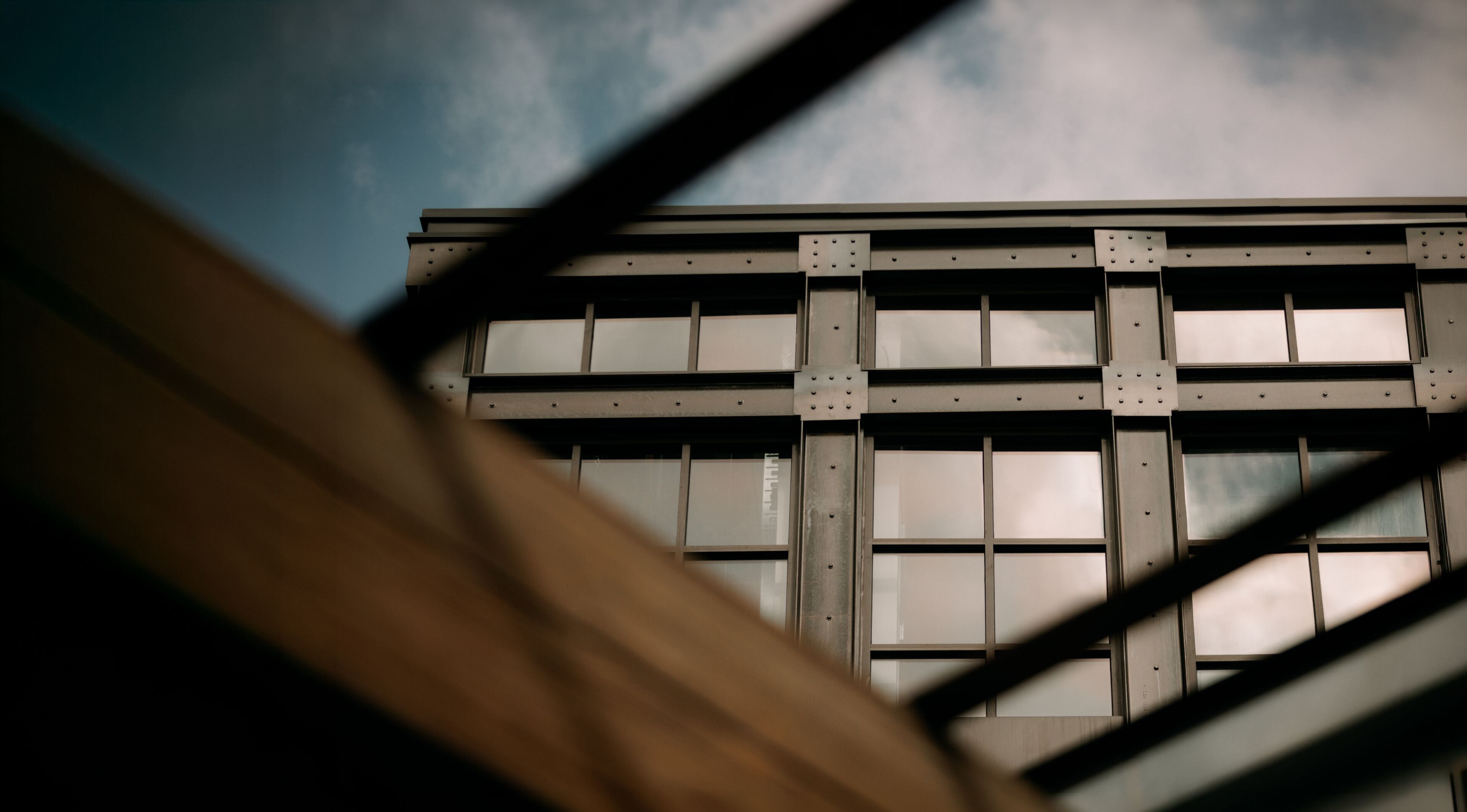 A building with a grid-like facade and large windows, viewed through a metal framework.