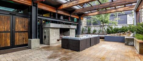 An outdoor patio with a stone floor, a built-in fire pit, and a seating area.