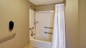 Une salle de bain avec une baignoire blanche, un rideau de douche, un porte-serviettes et un sèche-mains.