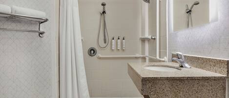 A modern bathroom with a shower, a sink, and a mirror.