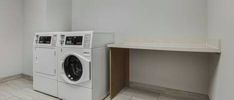 A laundry room with two stacked washing machines and a built-in shelf.