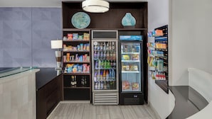 A modern hotel lobby with a glass counter, vending machines, and a decorative wall. - SpringHill Suites by Marriott Jacksonville North I-95 Area (Jacksonville)