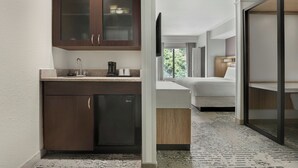A modern kitchen with dark wooden cabinets, a built-in dishwasher, and a countertop with a coffee maker. - SpringHill Suites by Marriott Jacksonville North I-95 Area (Jacksonville)