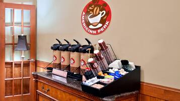 A coffee station with multiple coffee dispensers, a coffee urn, and a variety of coffee cups and mugs.