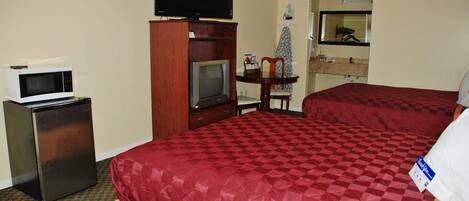 A hotel room with a bed, a television on a stand, a microwave, and a small refrigerator.