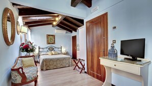 Un dormitorio con cama, una silla, un escritorio y una televisión.