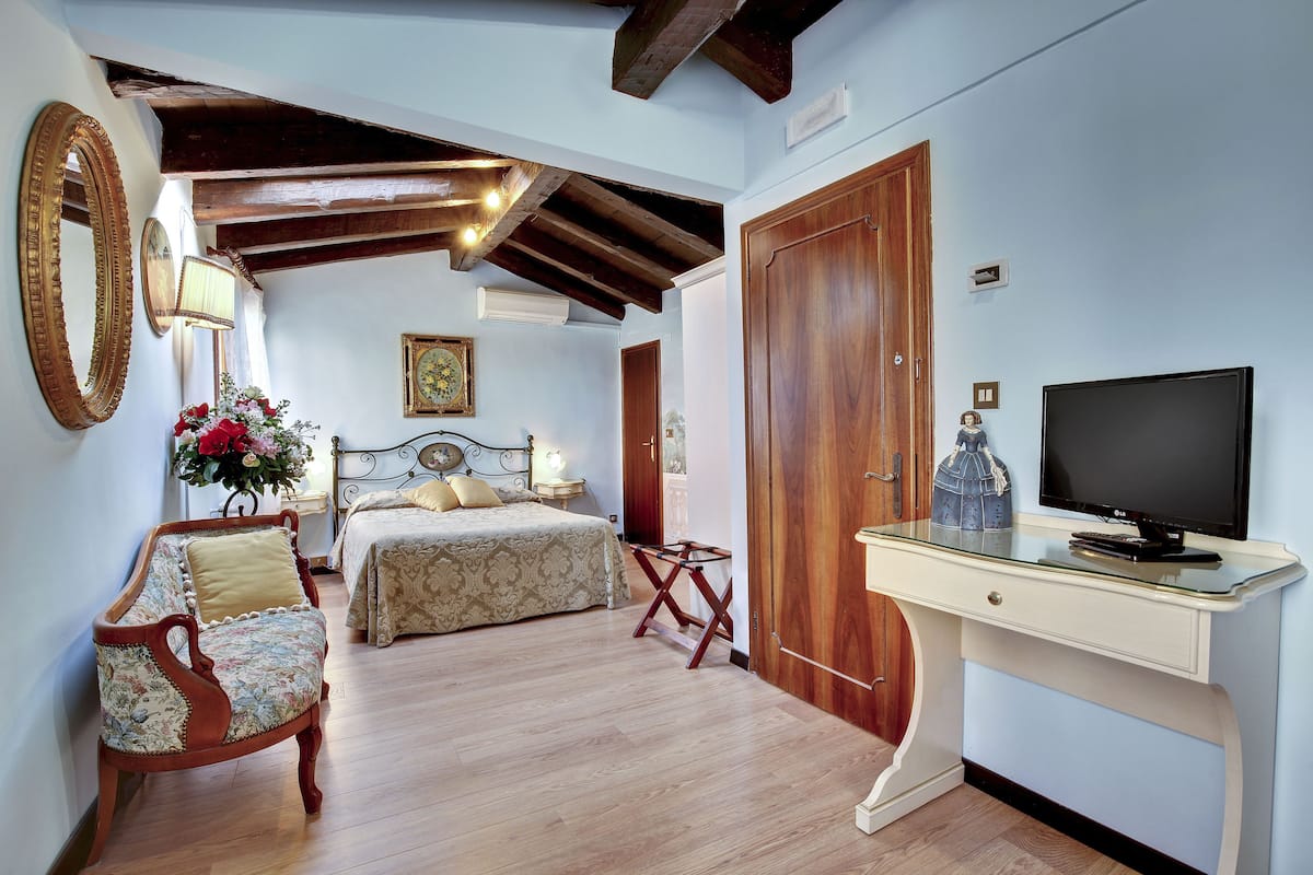 Un dormitorio con cama, una silla, un escritorio y una televisión.