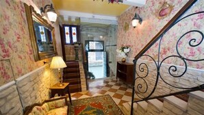 Una escalera con piso de tablones que lleva a una puerta, un sofá estampado con motivos florales y una alfombra con diseño.
