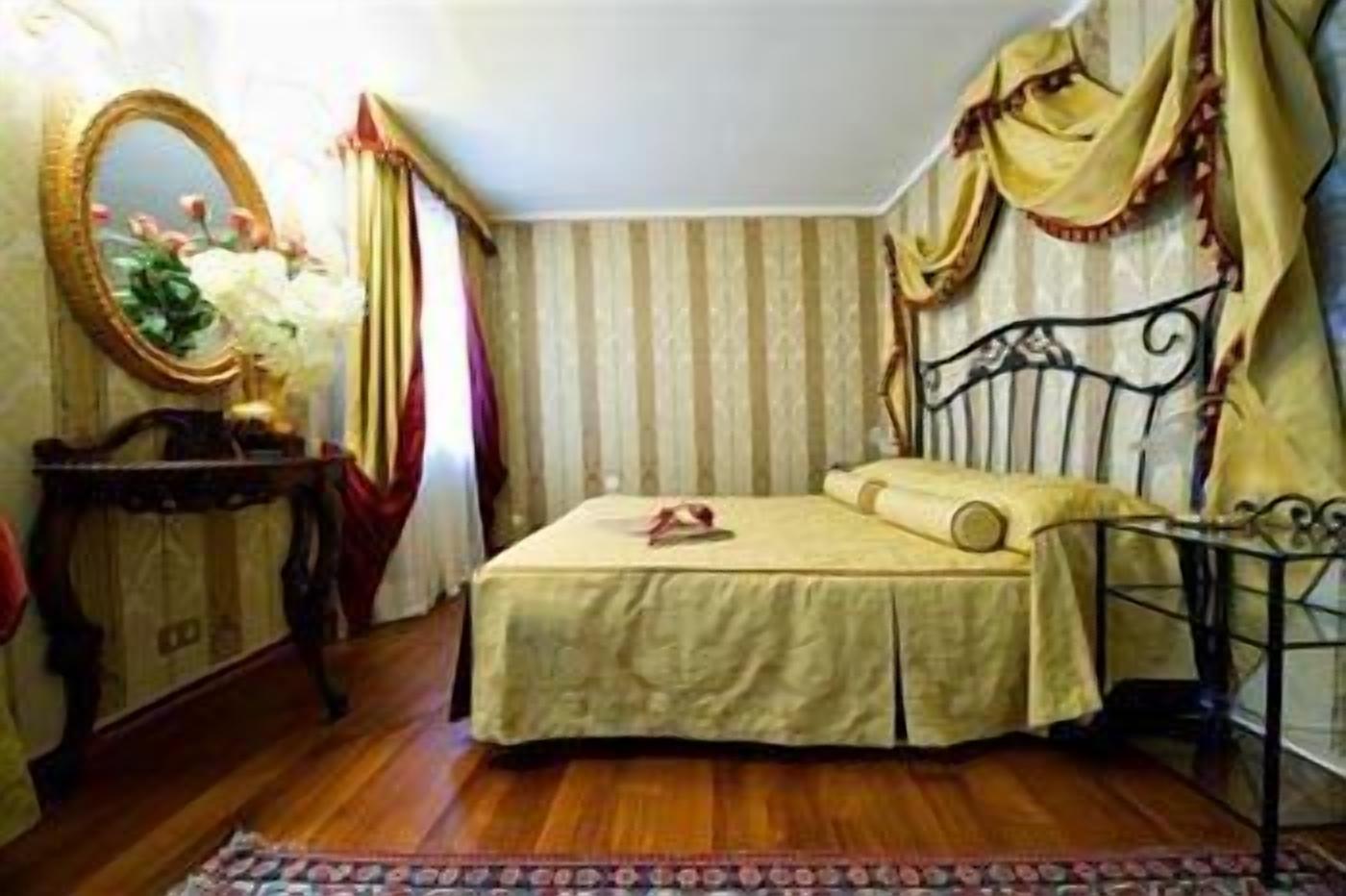 Une chambre à coucher avec un lit, une table de chevet, un miroir, des rideaux et un tapis à motifs.