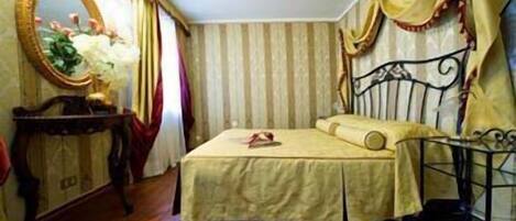Une chambre à coucher avec un lit, une table de chevet, un miroir, des rideaux et un tapis à motifs.