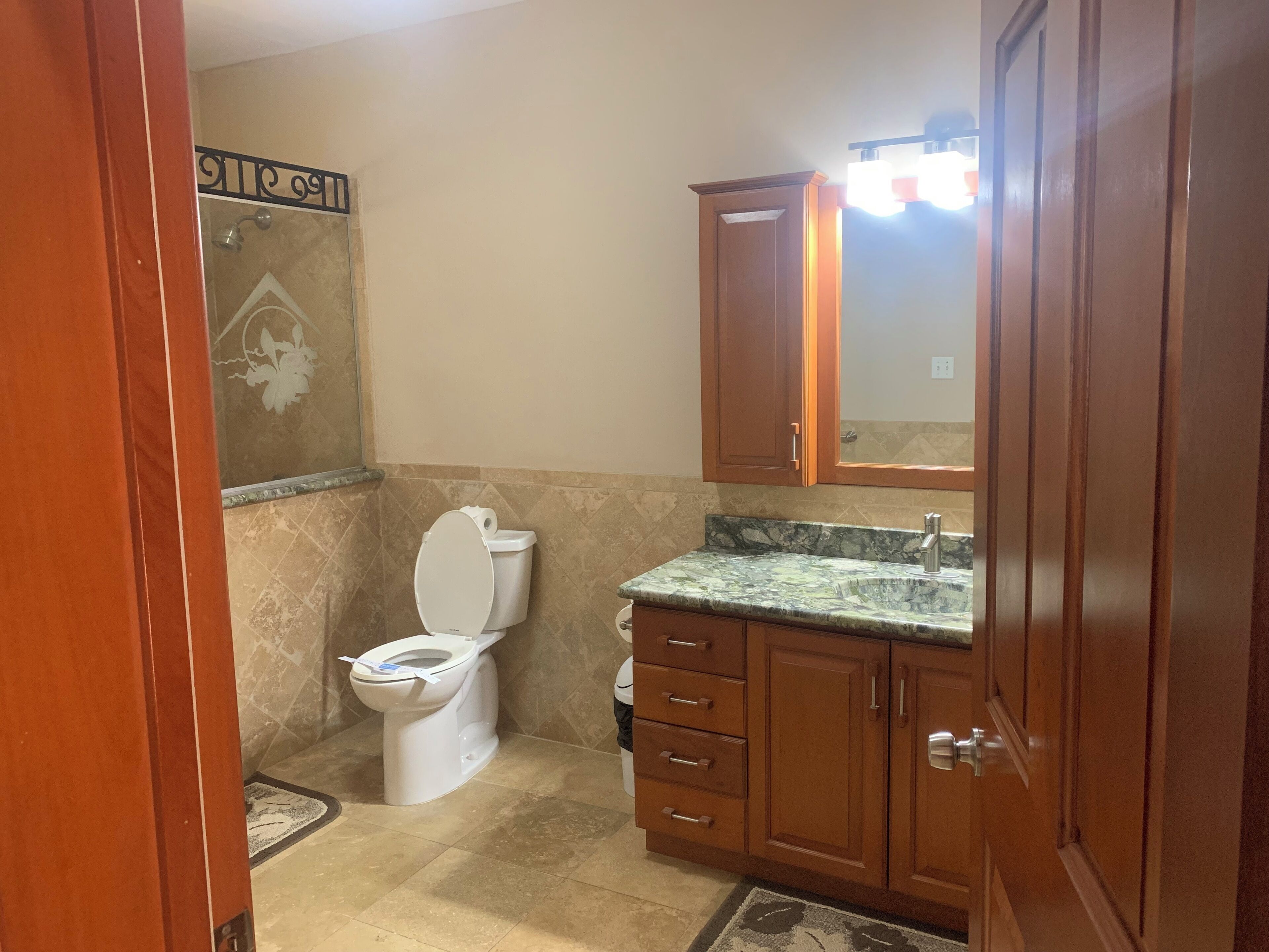 A bathroom with a toilet, sink, vanity, and a shower area.