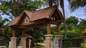 A wooden structure with a thatched roof, stone pillars, and a sign indicating a restaurant and bar. - Black Orchid Resort (Burrell Boom)