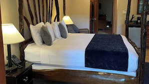 A four-poster bed with a rustic wooden frame, a white bedspread, and two bedside lamps. - Black Orchid Resort (Burrell Boom)