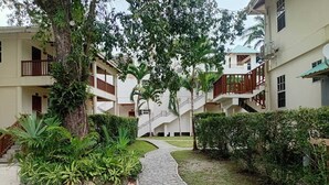 A courtyard with a central stone pathway, surrounded by lush greenery and multi-story buildings with balconies. - Black Orchid Resort (Burrell Boom)