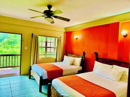 Habitación de hotel con dos camas, ventilador de techo, ventana con cortinas y vistas a zonas verdes.