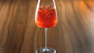 A clear glass of red beverage on a wooden surface.
