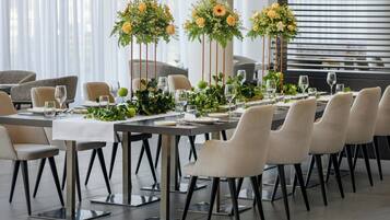 En matplats med bord som är dukade för sex personer, varje bord har en vit duk, matchande stolar och blomsterarrangemang som mittpunkt.