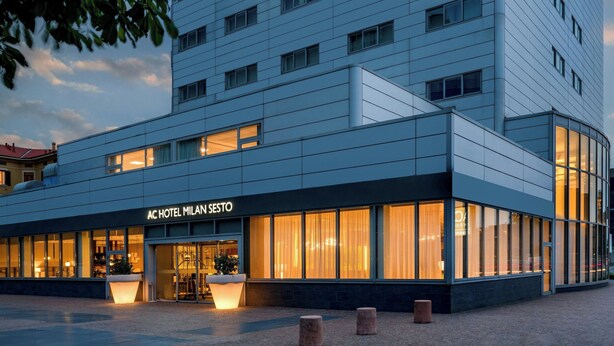 A modern hotel with a flat facade, large windows, and a well-lit entrance. - AC Hotel by Marriott Milan Sesto (Sesto San Giovanni)