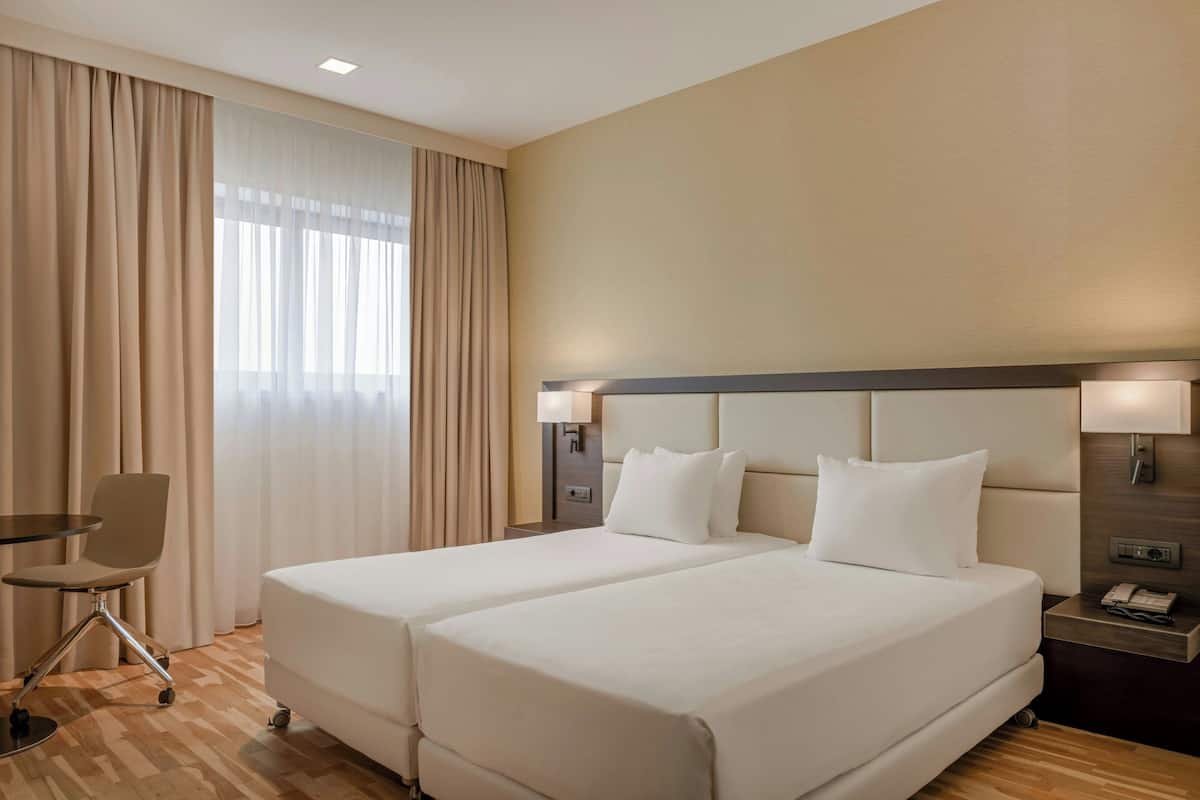 Ein Hotelzimmer mit zwei Betten, einem Schreibtisch und einem Stuhl.